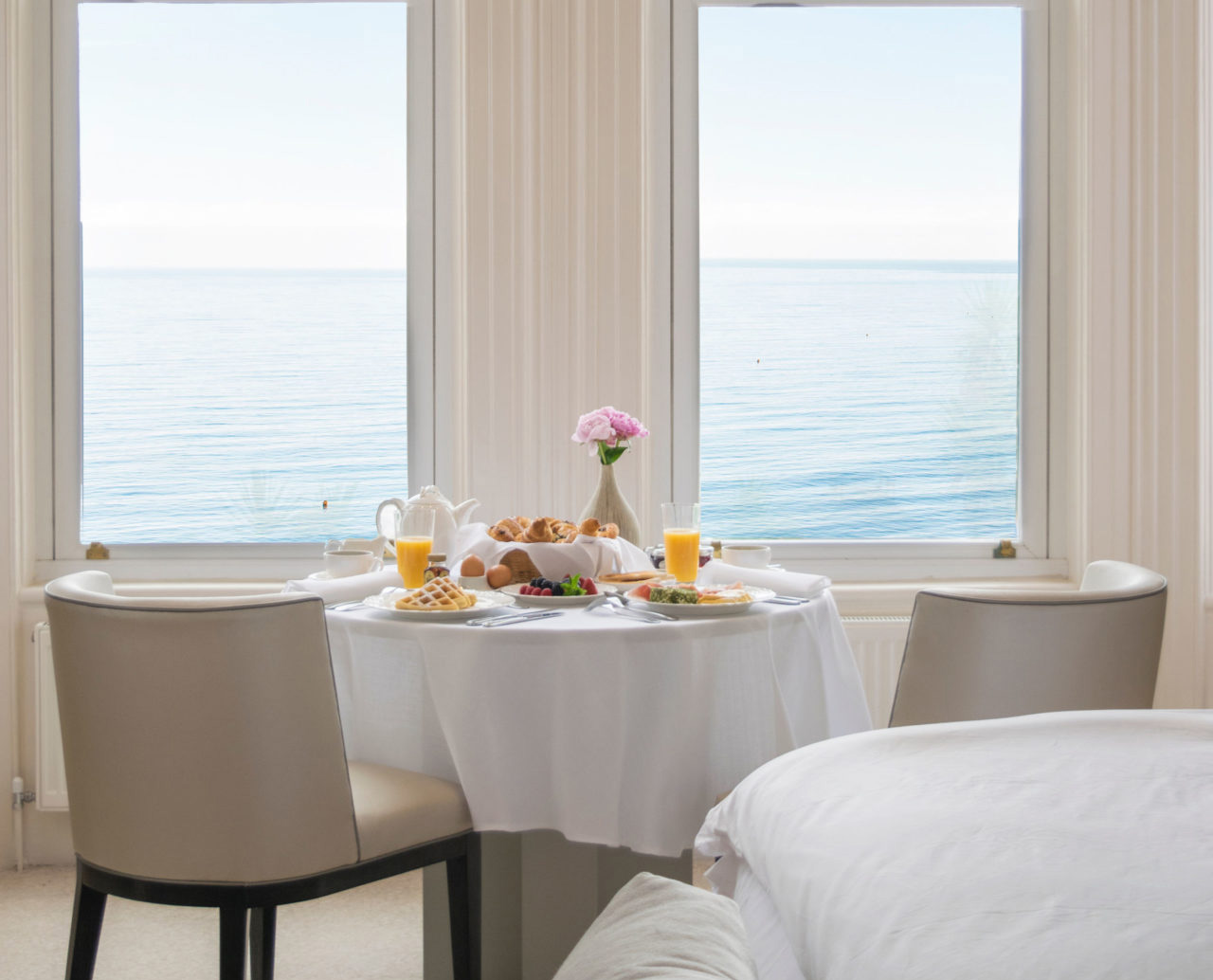 Breakfast laid on a table beside two windows overlooking the sea